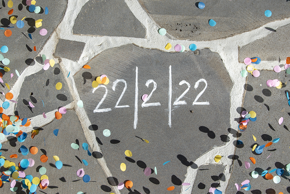 The date 22/2/22 written on stone paving, with white chalk. With coloured confetti flying all around